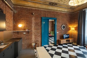 A room with a brick wall, a checkered floor, a blue door, a clock, and a television.