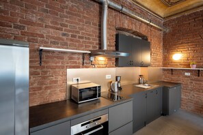 A modern kitchen with a brick wall, stainless steel appliances, and a built-in oven.