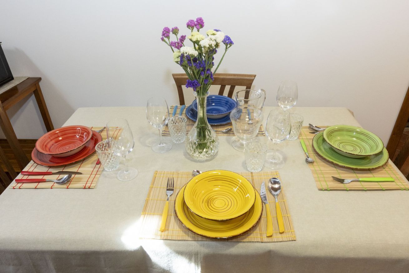 A dining table set with plates, cutlery, and a vase of flowers.