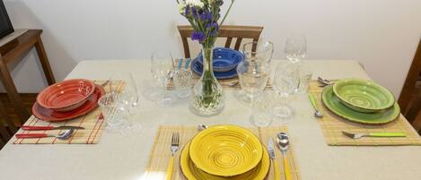 A dining table set with plates, cutlery, and a vase of flowers.