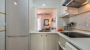 Une cuisine avec des armoires blanches, un four encastré, un évier et une cuisinière.