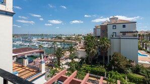 Un port de plaisance avec des bateaux, un bâtiment doté d’un balcon et des palmiers.
