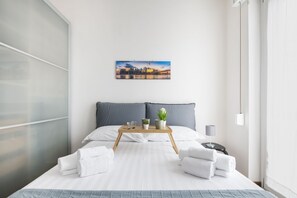 Ein modernes Hotelzimmer mit Bett, Nachttisch, Fenster und einem Gemälde an der Wand.