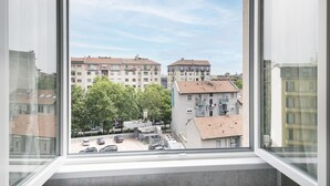 A view from a window overlooking a parking lot and buildings with multiple floors and balconies. - Easylife - Modern apartment in Bocconi (Milano)