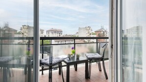 A balcony with a table and chairs, overlooking a cityscape. - Easylife - Modern apartment in Bocconi (Milano)