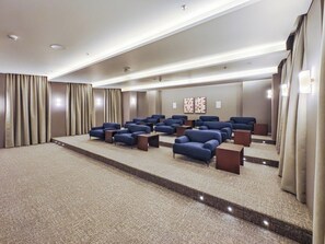 Ein Hotelzimmer mit Teppichboden, einer Sitzecke mit Sofas und Tischen sowie Vorhängen an den Fenstern.