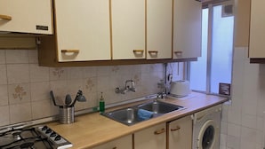 Una cocina con estufa a gas, lavamanos y lavadora.