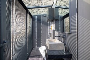 Een moderne badkamer met een grote spiegel, een marmeren wastafel en een douchehoek.