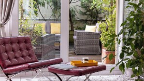 Un salon moderne avec un fauteuil en cuir, une petite table et un canapé en osier agrémenté de coussins.