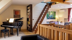 Un vaste espace de vie agrémenté d’un magnifique piano à queue, d’un escalier en bois et d’un coin repas doté de meubles modernes.