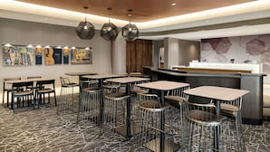 A modern restaurant with multiple tables and chairs, a wooden ceiling, and contemporary artwork on the walls. - SpringHill Suites® by Marriott® Easton Bethlehem (Easton)