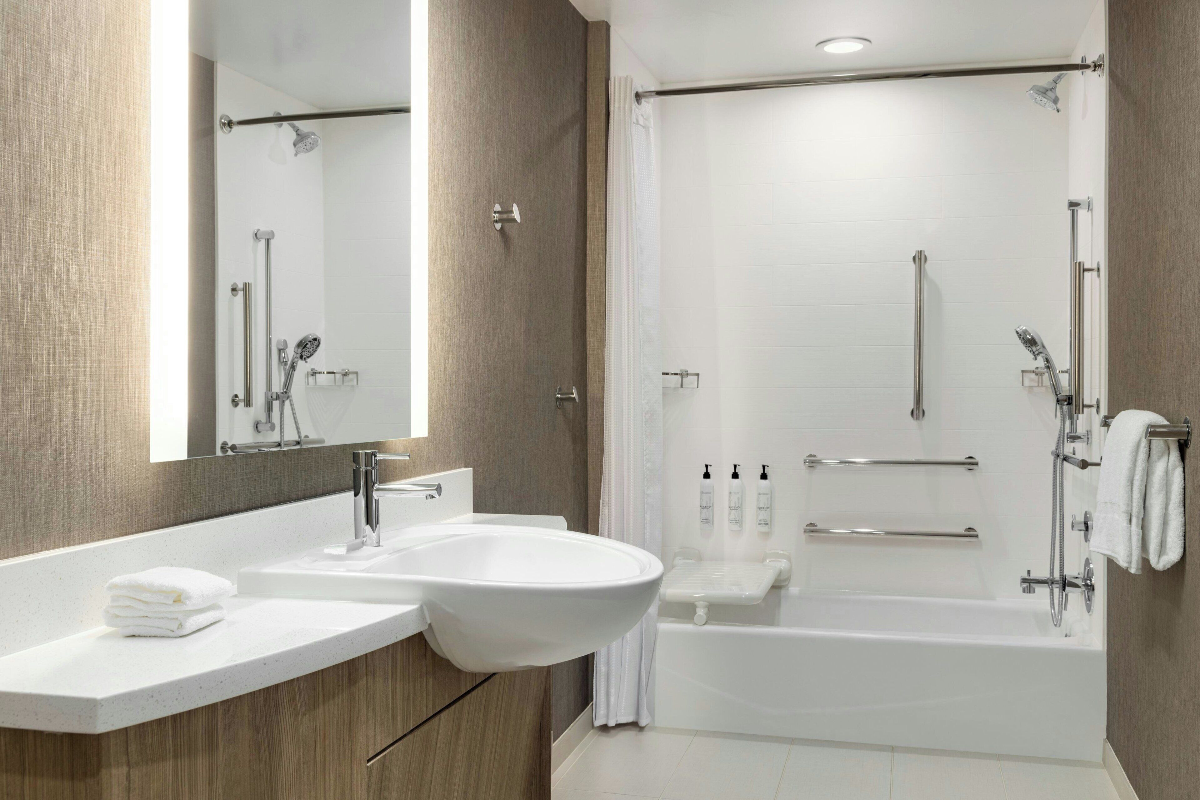 A modern bathroom with a large sink, mirror, and a walk-in shower.