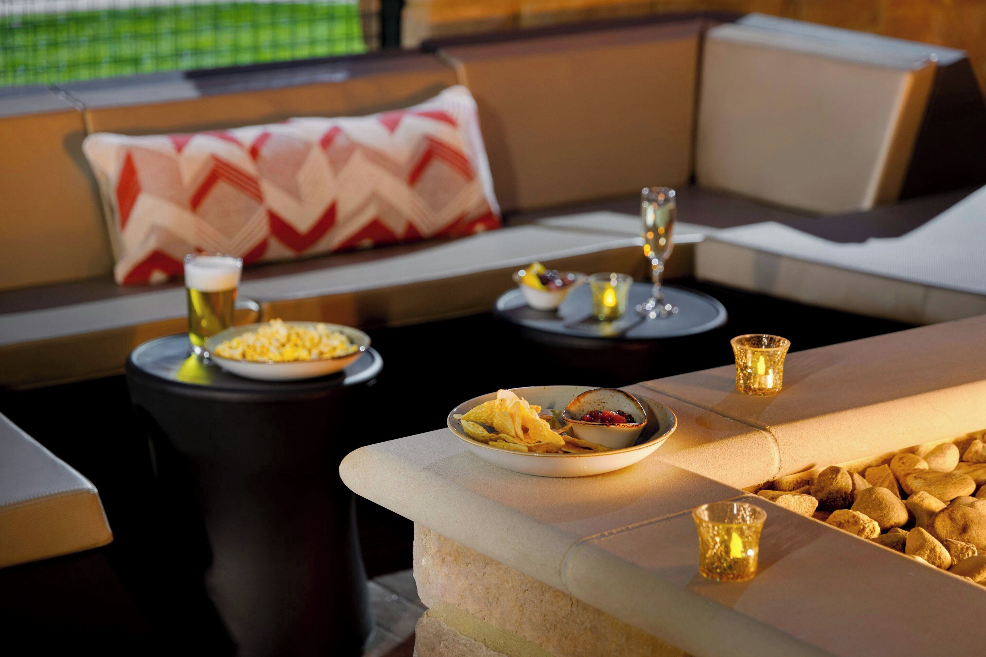 A dining area with a sofa, a table with plates of food, glasses, and candles.