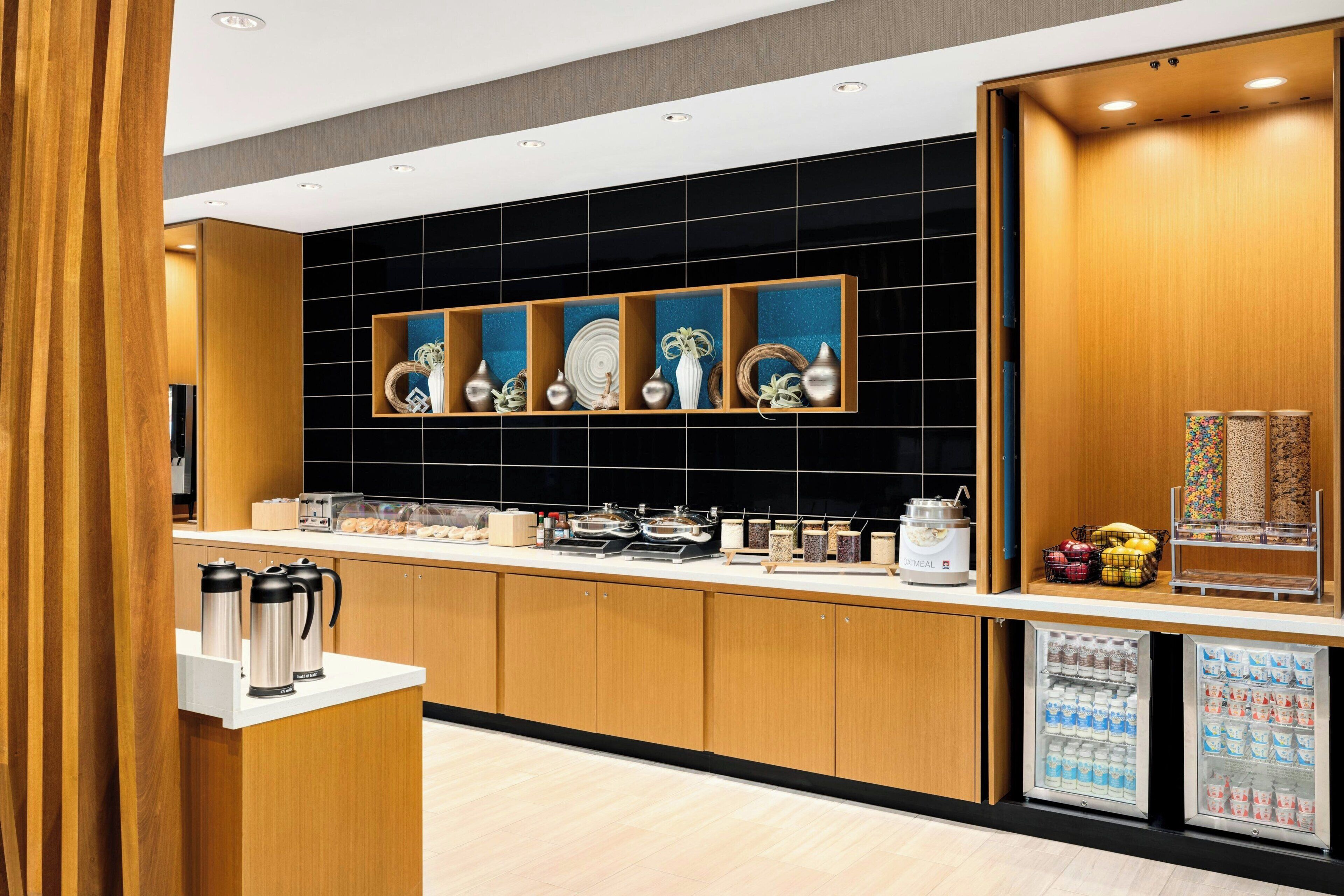 Cozinha moderna com armários de madeira, painel de azulejos pretos e um espaço para café.