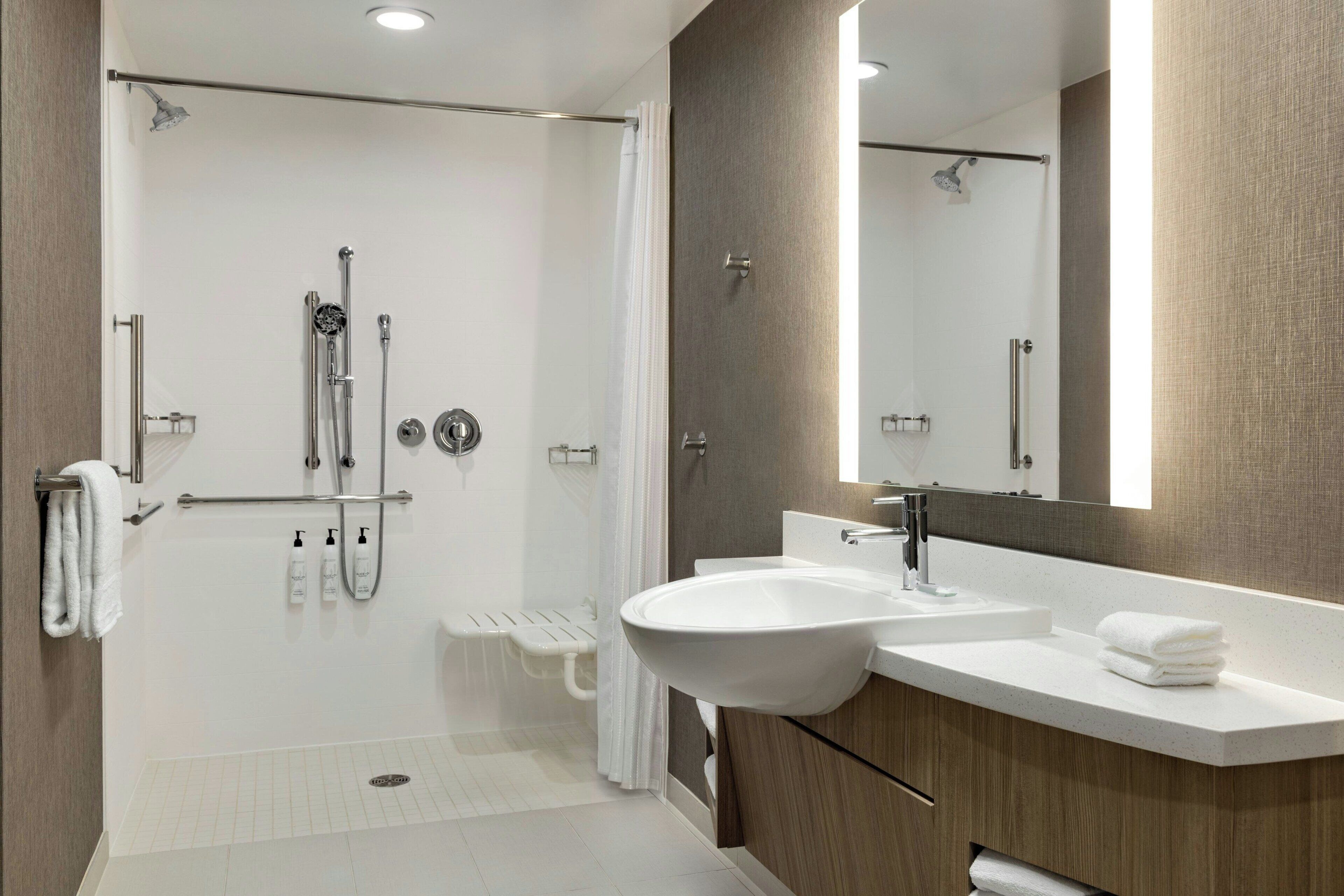 A modern bathroom with a shower, sink, and vanity.