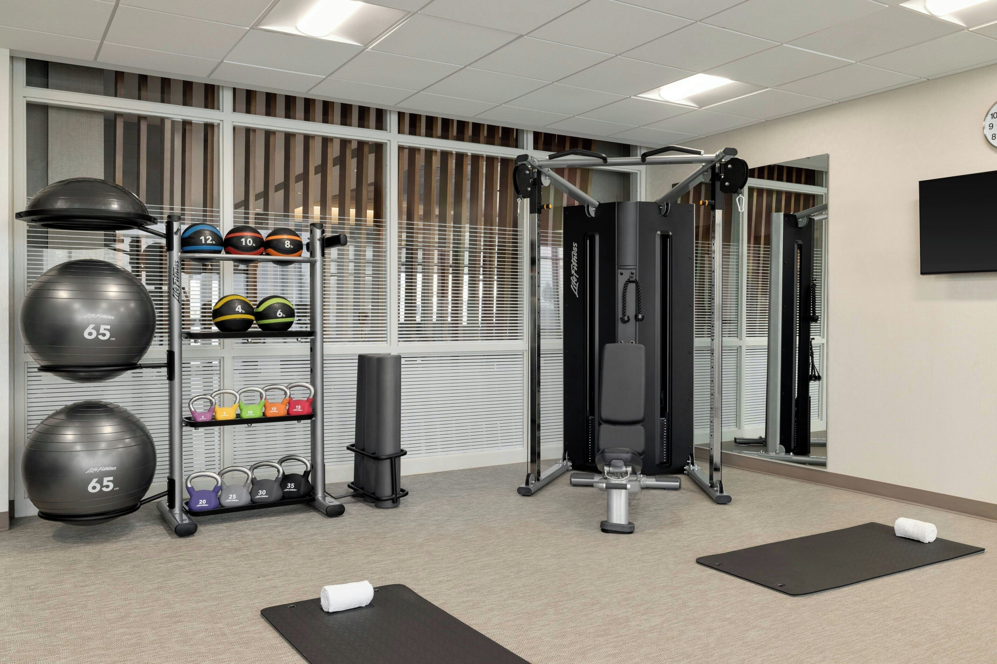 Une salle de sport équipée de matériel d’exercice, de poids et d’un miroir.