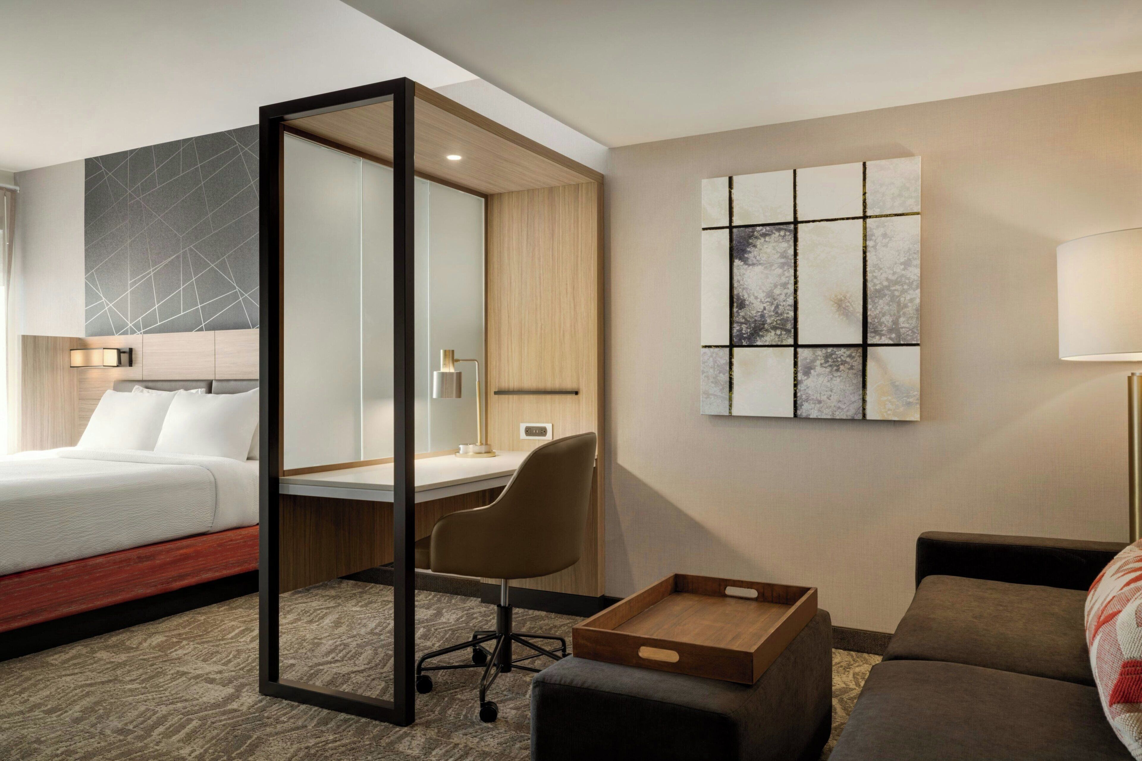 Una habitación de hotel con cama, escritorio, silla y una mesita.