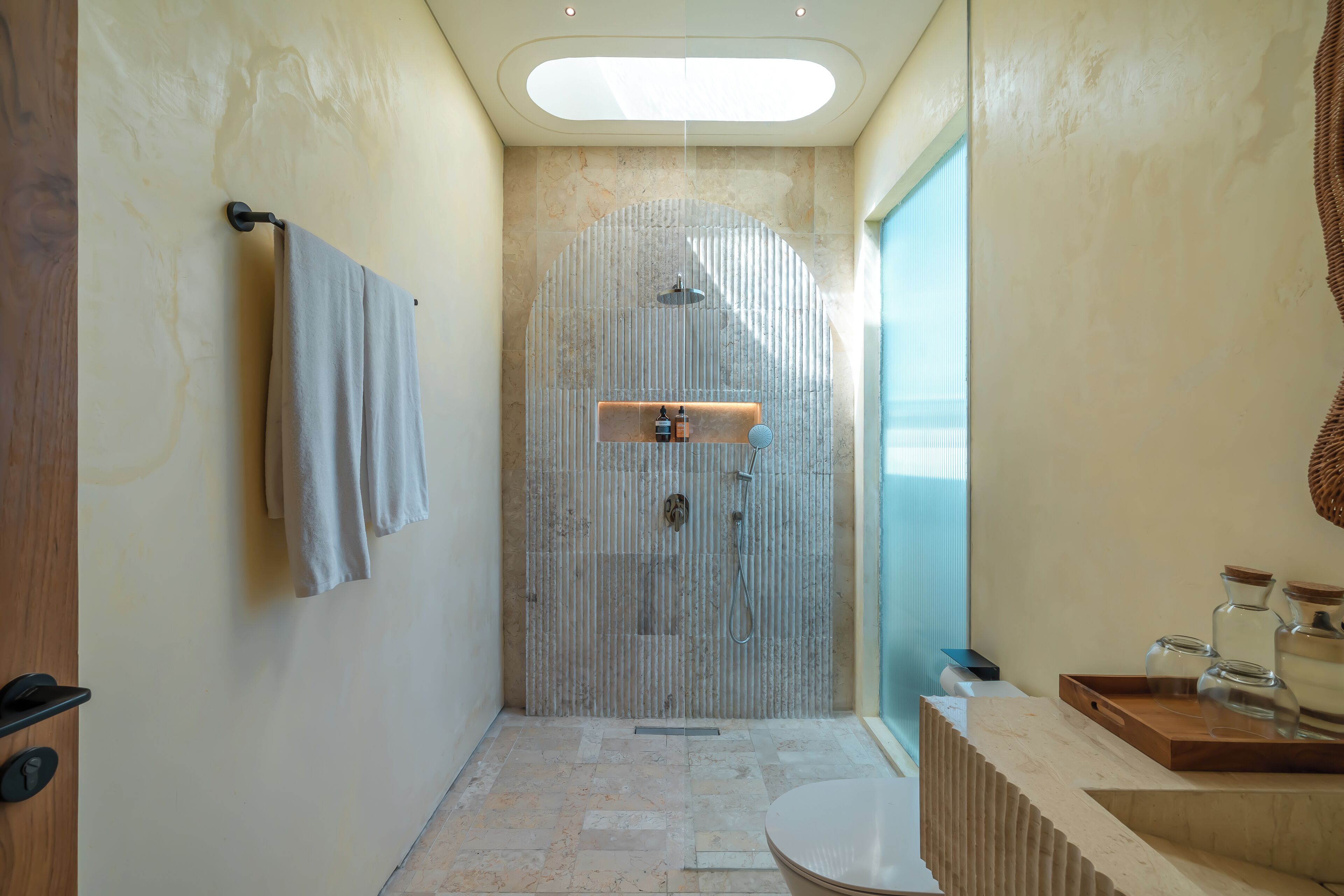 A modern bathroom with a shower, a sink, and a glass partition.