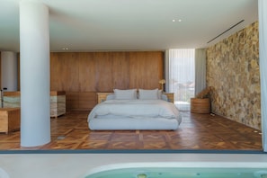 Ein modernes Schlafzimmer mit einem großen Bett, Holzwandverkleidung und einer Wand aus Stein.