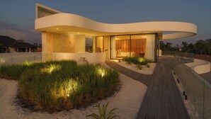 A modern house with a curved design, large windows, and a wooden deck. - Babylon (Cemagi)