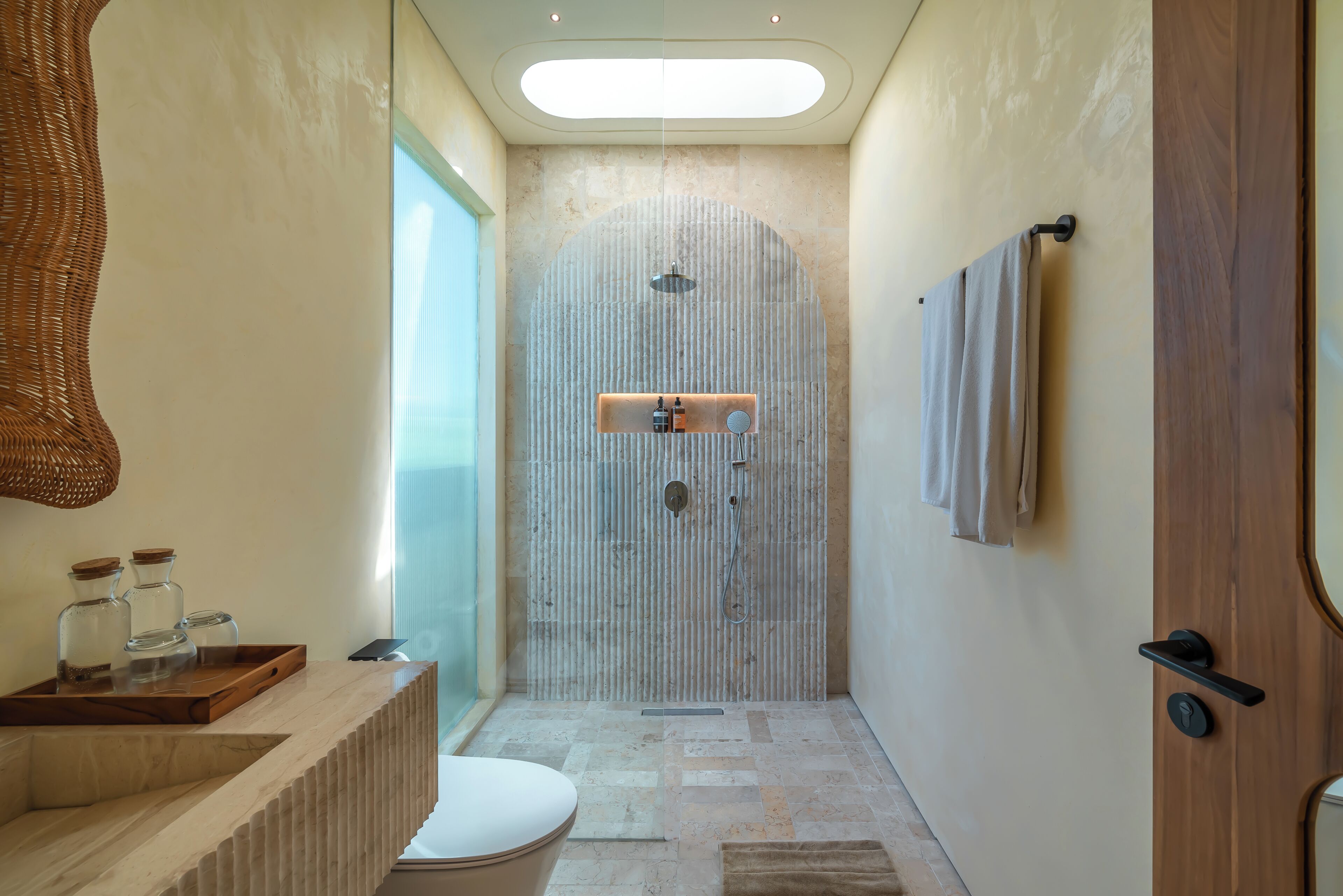 Une salle de bain moderne équipée d’une douche, de toilettes et d’un meuble-lavabo en bois.