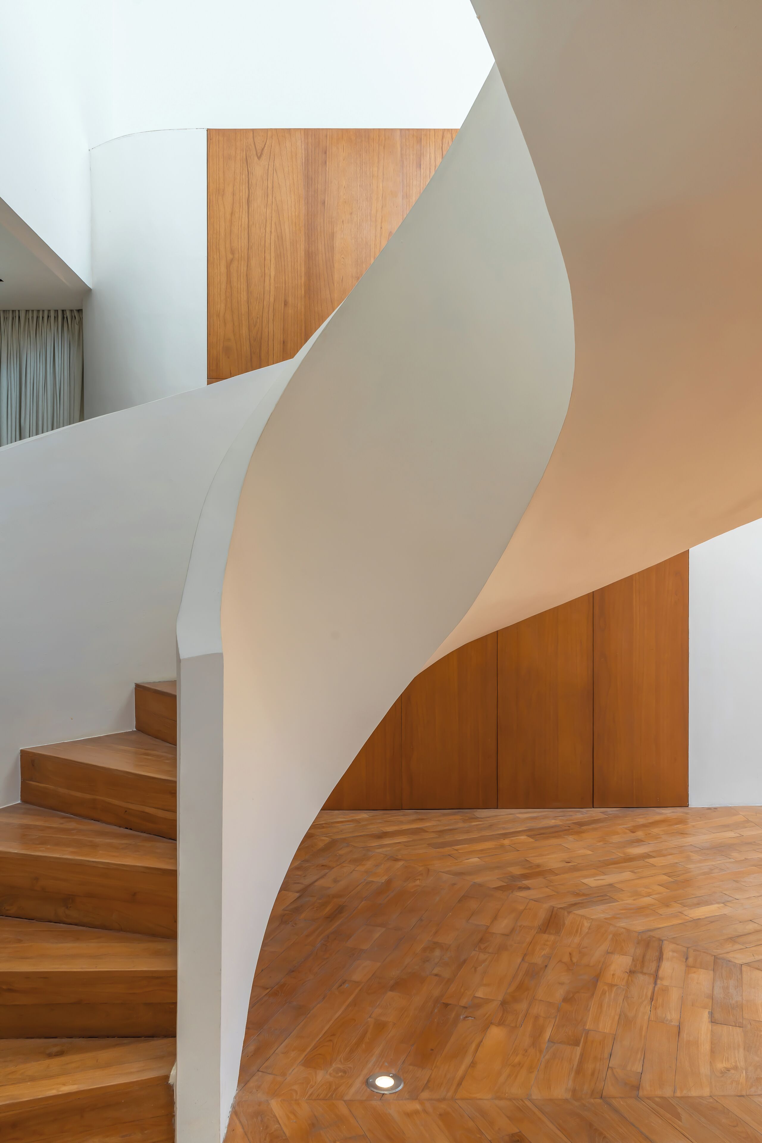 Un escalier en colimaçon moderne, avec des marches en bois et des murs blancs.