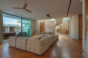 A spacious living area with a large sectional sofa, a wooden coffee table, and a ceiling fan.