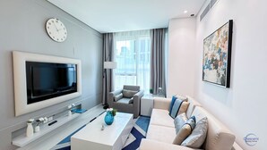 A modern living room with a flat-screen TV, a sofa, a coffee table, and a large window with curtains. - Chic One Bedroom Near Dubai Mall in Damac Voleo (Business Bay)