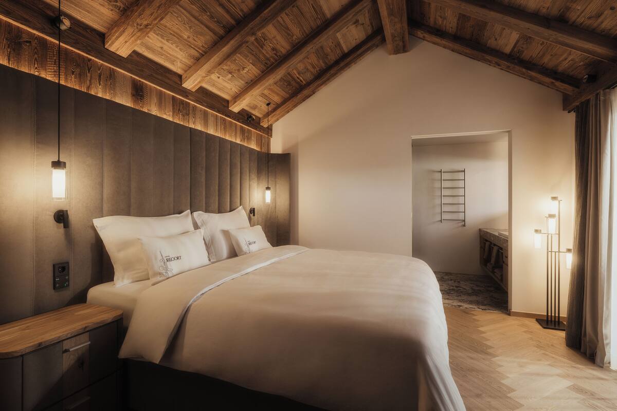 Ein Schlafzimmer mit Holzboden, einem Bett mit weißer Bettwäsche, Nachttischlampen und einem Nachttisch.