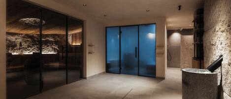A modern hotel lobby with a stone wall, a glass door, and a stone pillar.