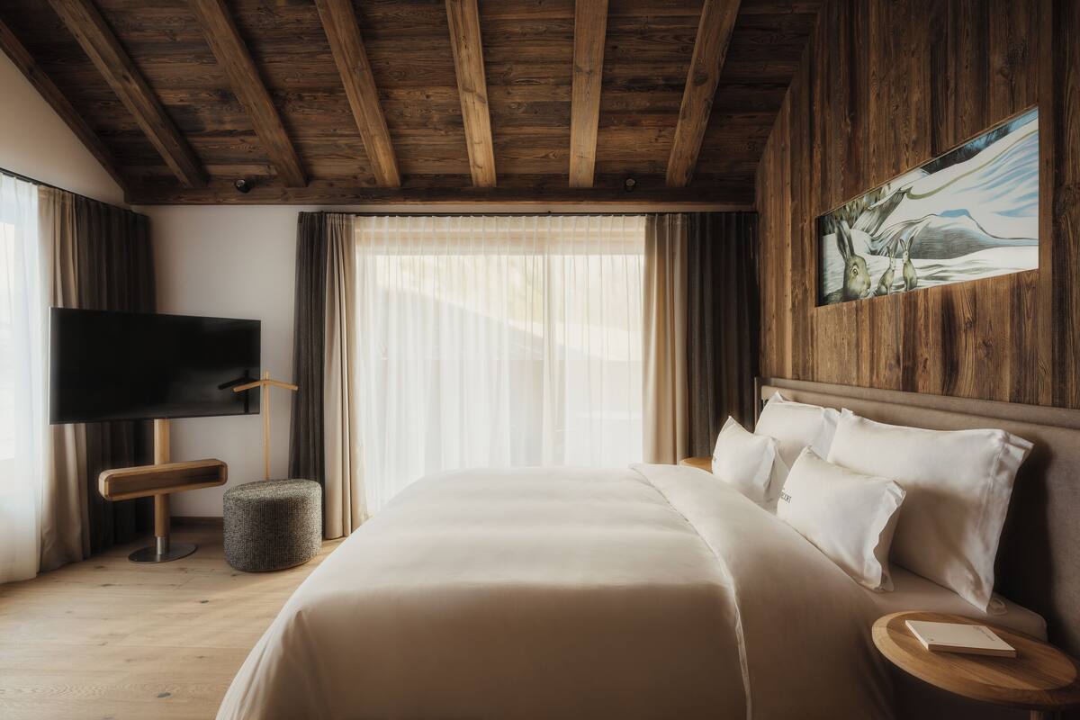 Ein Schlafzimmer mit einem großen Bett, einem Flachbildfernseher, Holzboden und einem Bild an der Wand.