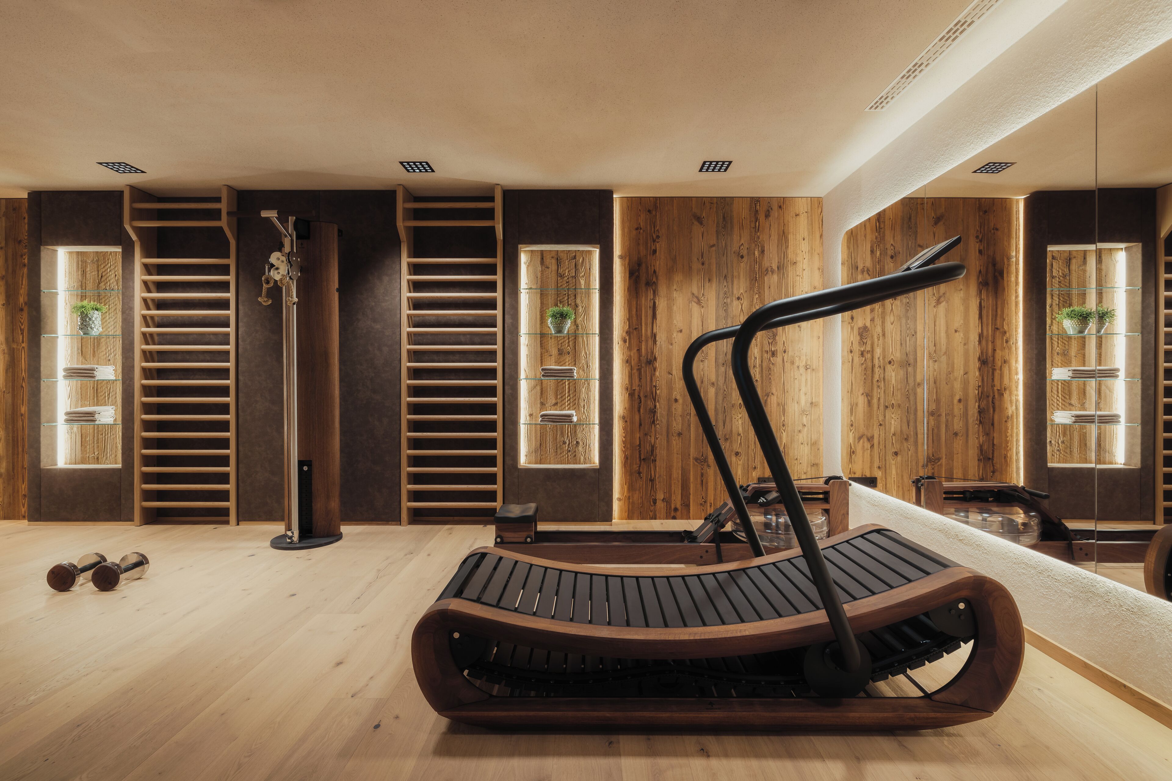 Une salle de sport moderne avec des murs en bois, un tapis de course, des haltères et un escalier.