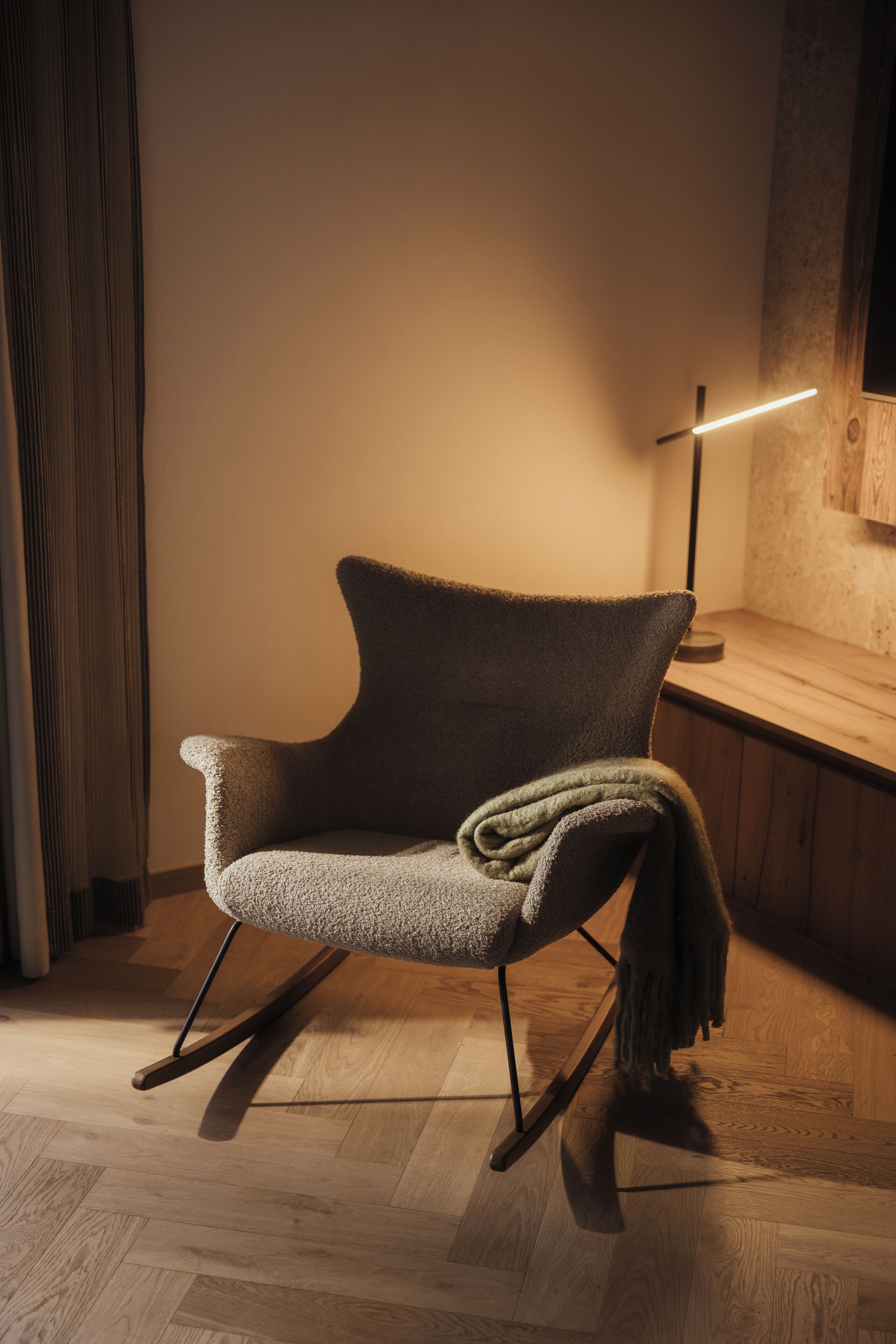 A modern chair with a wooden base and a light fixture in the background.