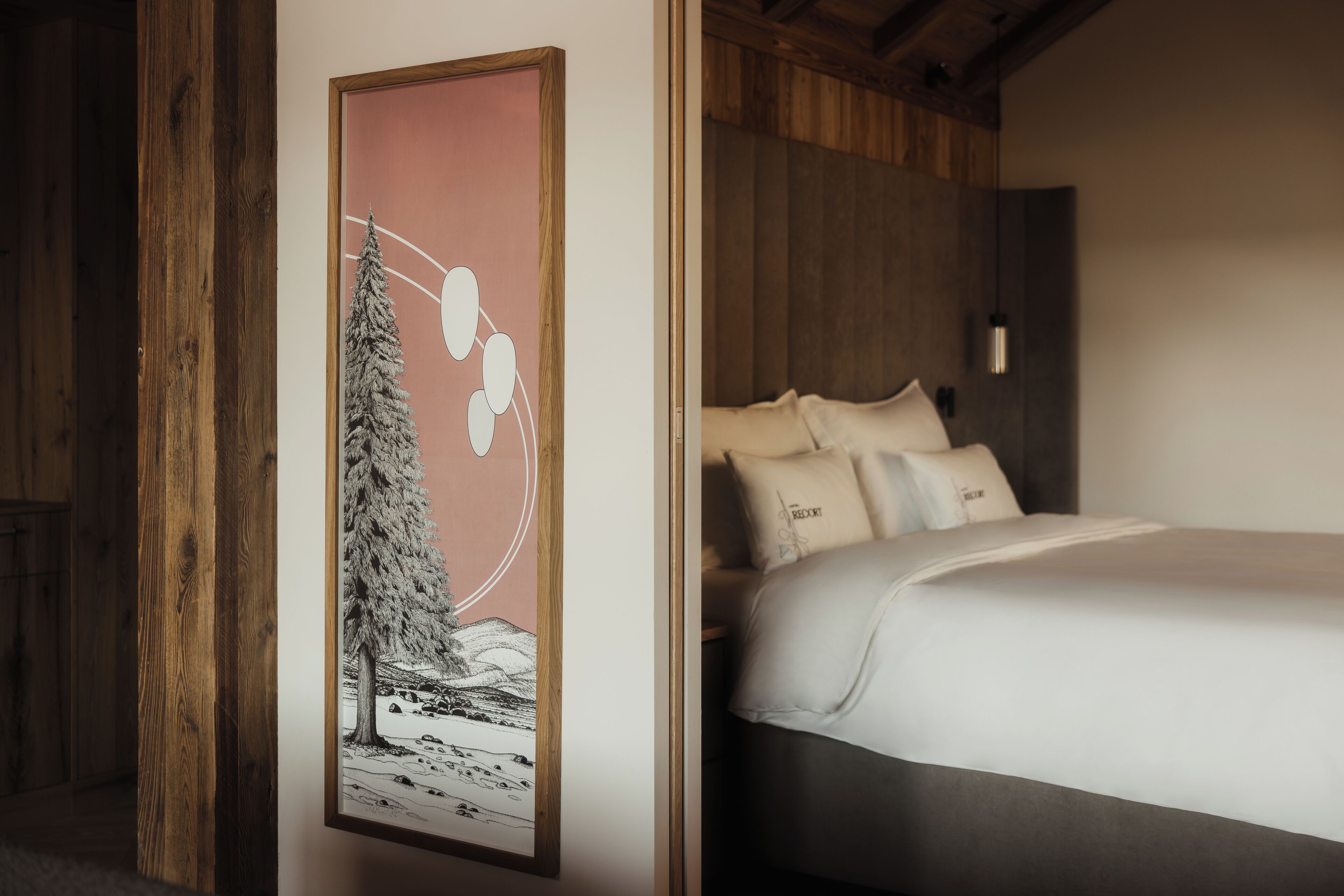 Un dormitorio con cama, almohadas y una obra de arte enmarcada en la pared.