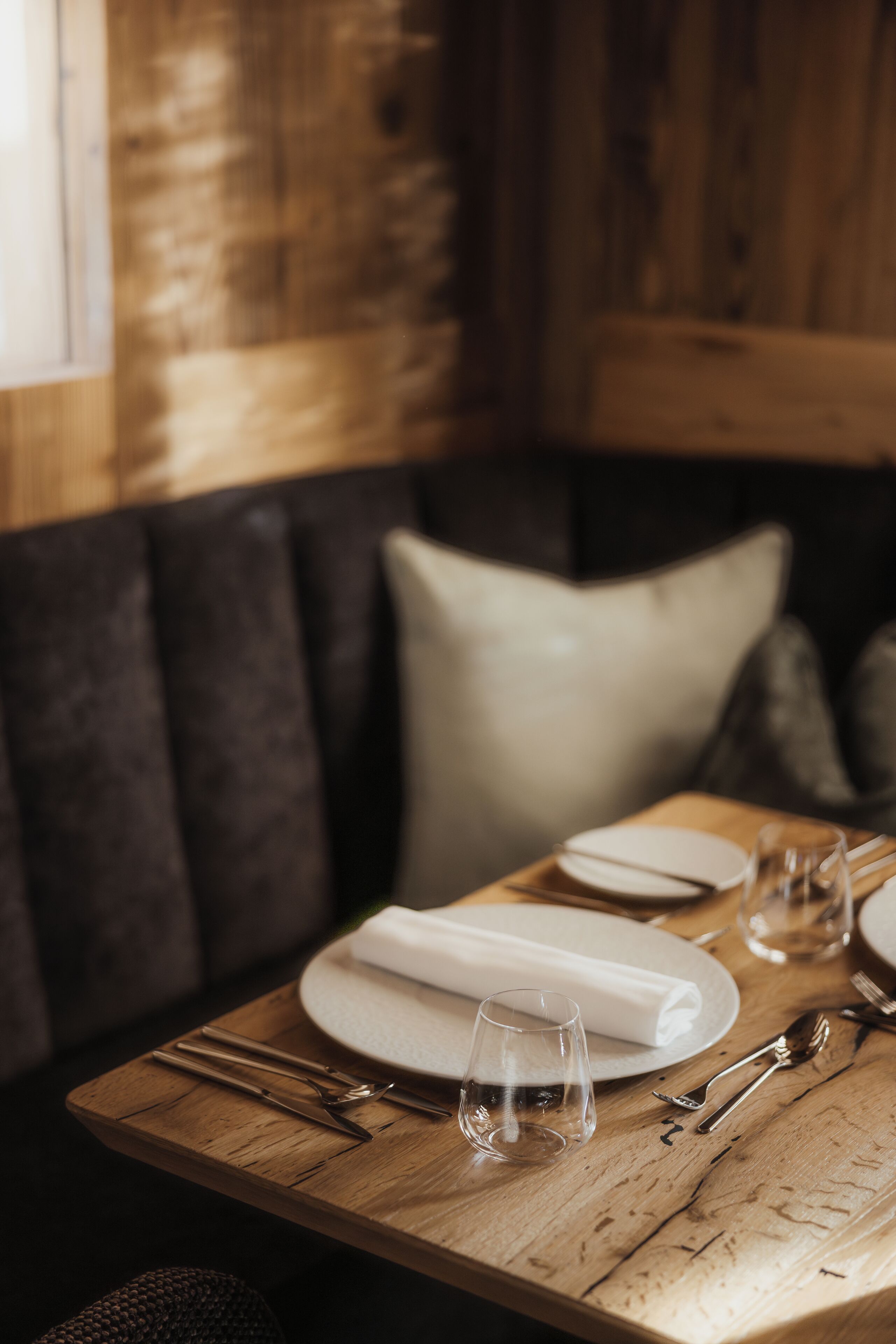 Ein Esszimmer mit Holztisch, Geschirr, Besteck und einem Glas.