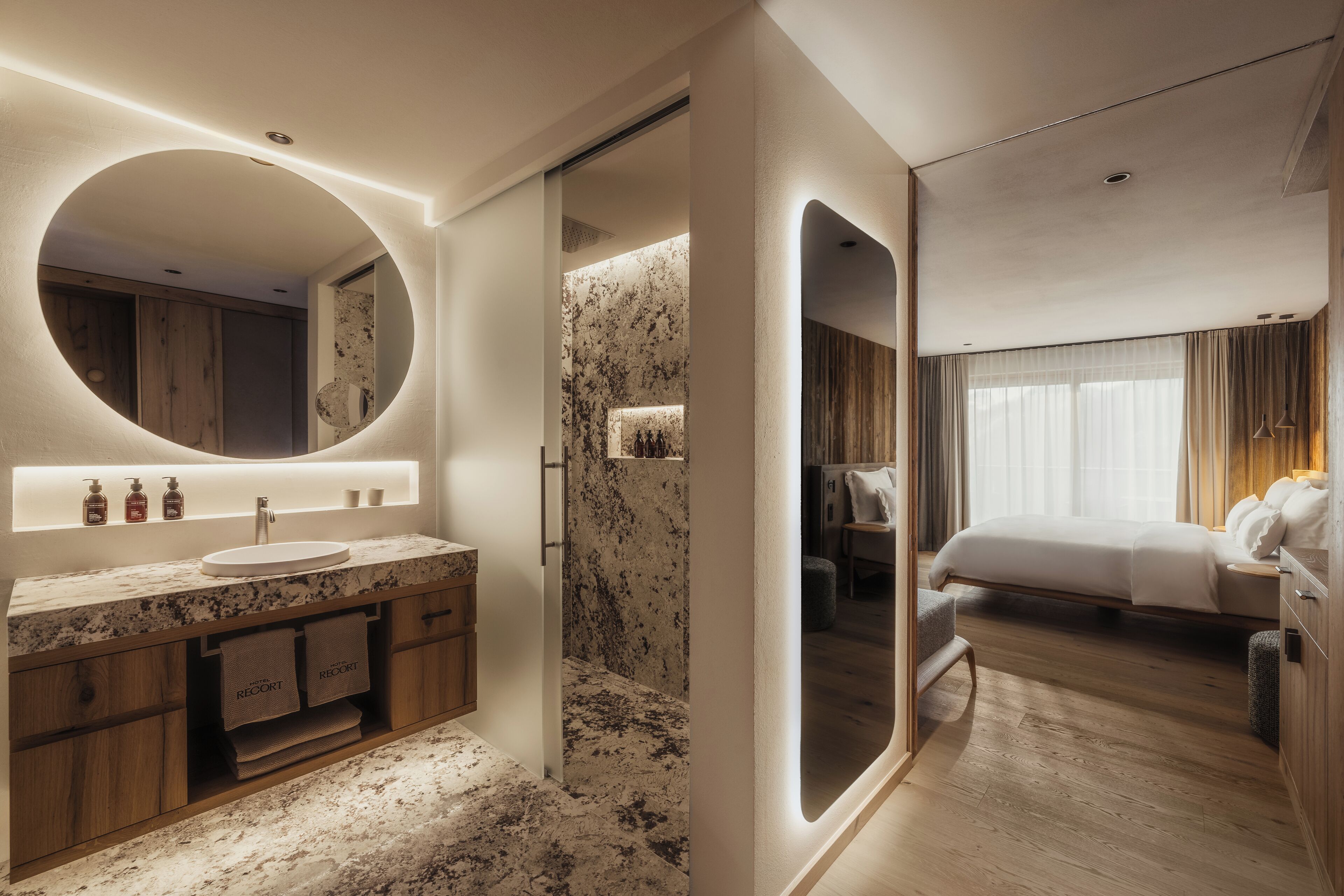 A modern bathroom with a marble sink, wooden cabinets, and a large mirror.