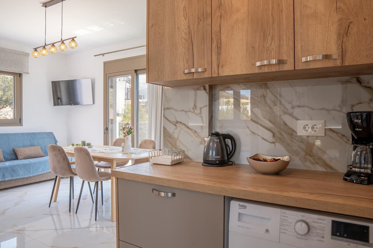 Una cocina moderna con armarios de madera, salpicadero de mármol y lavavajillas empotrado.