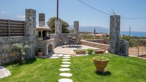 A stone patio with outdoor seating, a stone oven, and a view of the sea. - Villa Leandros With Pool & bbq (Agios Nikolaos)