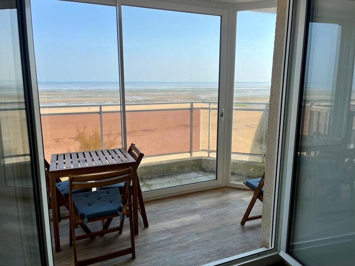 Un balcon avec une table et des chaises, donnant sur une plage.