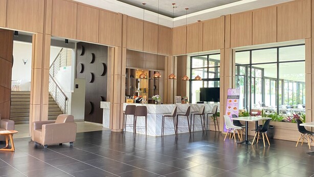 A modern interior with a central bar area, seating arrangements, and a staircase leading to an upper level. - NITE & DAY MDC Gadog (Megamendung)