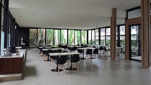 A spacious indoor dining area with high ceilings, large windows, and modern furniture. - NITE & DAY MDC Gadog (Megamendung)