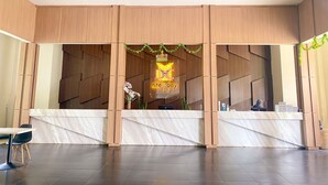 A hotel reception area with a marble counter, wooden paneling, and a neon sign. - NITE & DAY MDC Gadog (Megamendung)