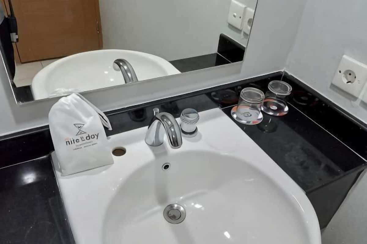 A white sink with a mirror above it, a towel dispenser, and a soap dispenser.