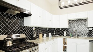A kitchen with white cabinets, a stainless steel stove, and a black tiled backsplash. - We can all stay together, everyone has room, the dog can come, and getting where we need to go is easy. (Montgomery)