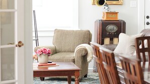 A room with a wooden coffee table, a beige armchair, a wooden dining table, and a vintage radio. - We can all stay together, everyone has room, the dog can come, and getting where we need to go is easy. (Montgomery)