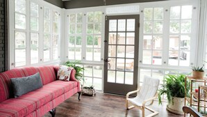 A room with a red sofa, a white chair, and a wooden table with plants. - We can all stay together, everyone has room, the dog can come, and getting where we need to go is easy. (Montgomery)