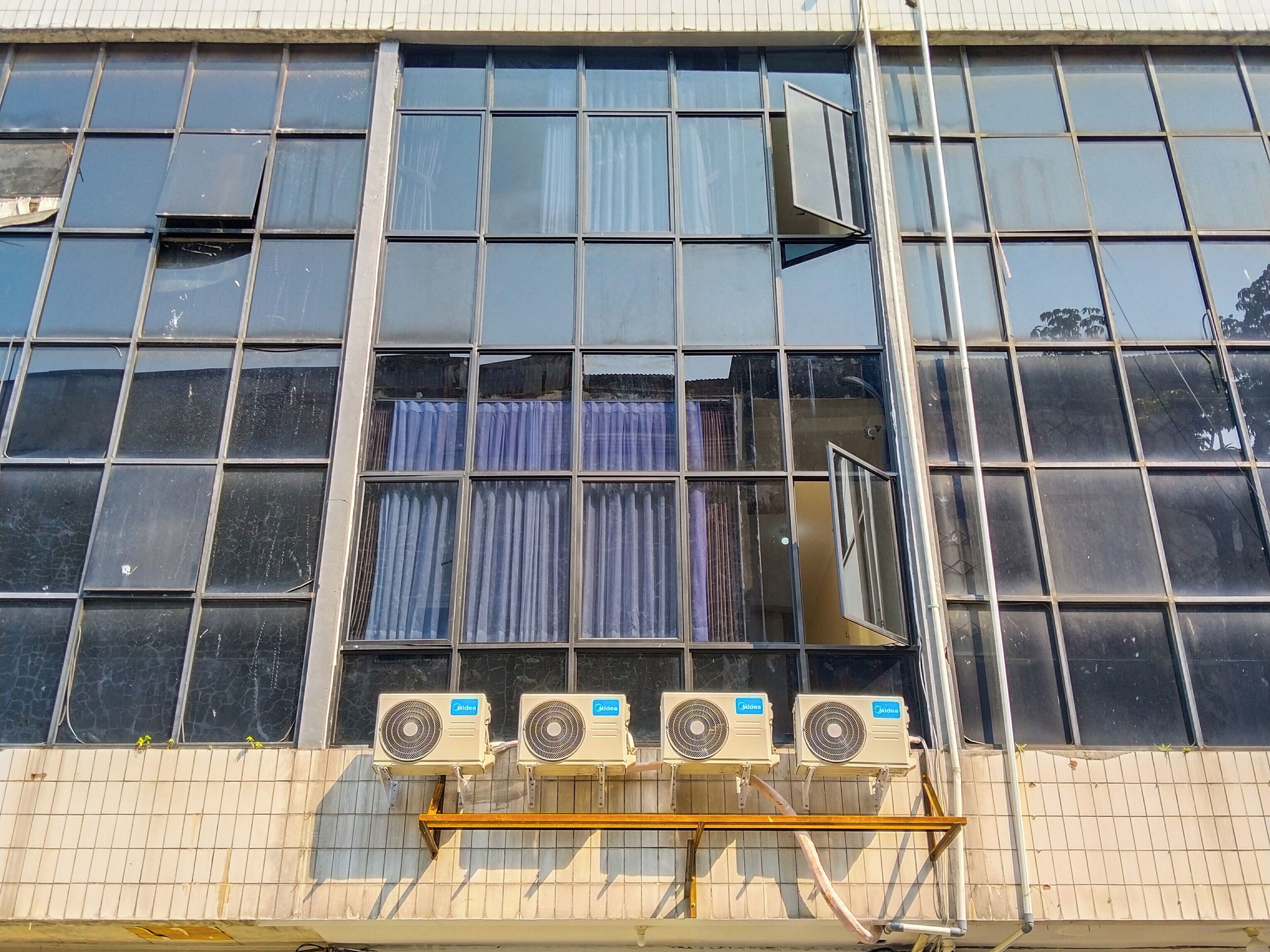 A building facade with large windows, air conditioning units, and a visible curtain.