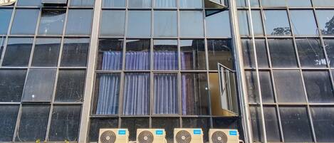 A building facade with large windows, air conditioning units, and a visible curtain.