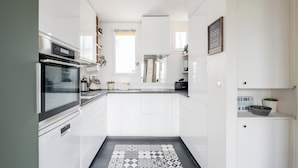 A modern kitchen with white cabinetry, a stainless steel oven, and a patterned tile floor.