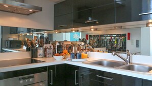 A modern kitchen with black cabinets, stainless steel appliances, and a variety of kitchen tools and appliances on the countertops. - L'Émeraude Malouine (Saint-Malo)